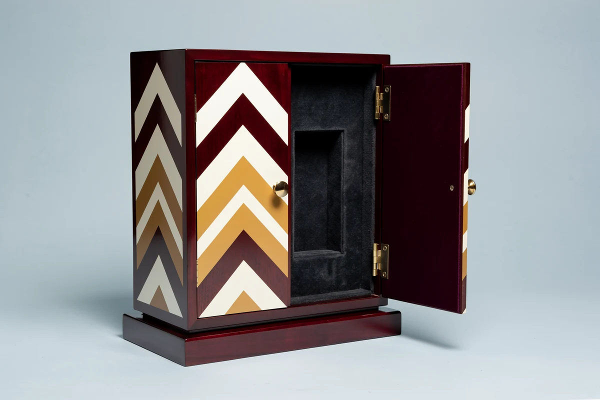 Burgundy wooden presentation case with ivory and ochre geometric graphics and one door open to a dark lined recess
