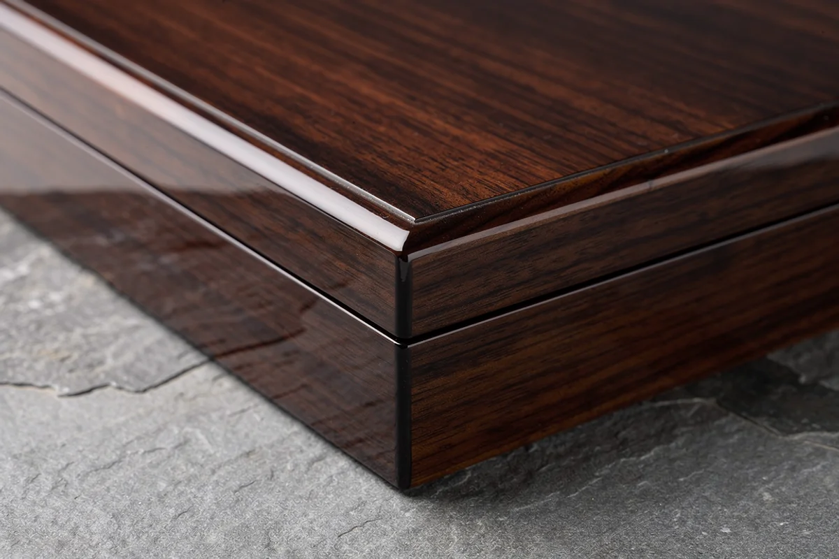 Close view of a clear-lacquered wood-grain box lid, narrow rim and corner