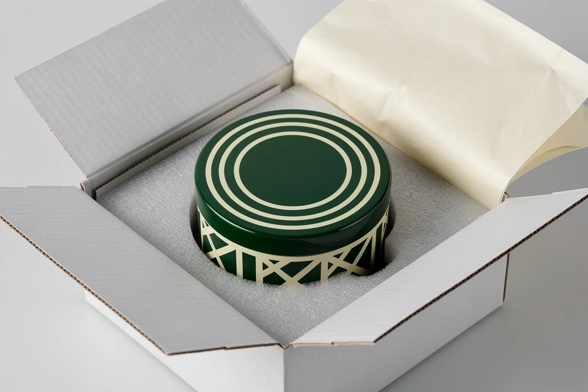 Round patterned wooden box nested in a protective cavity inside an outer carton