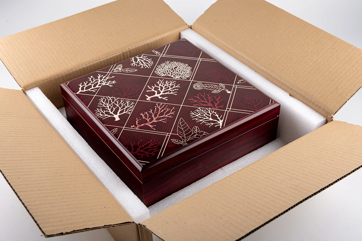 Burgundy patterned wooden box protected inside an open shipping carton
